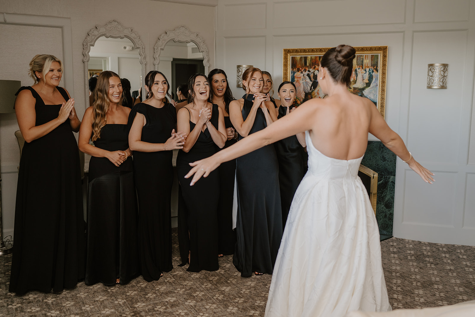Bridesmaids reacting with joyful gasps and applause during the bride's big reveal in her gown.
